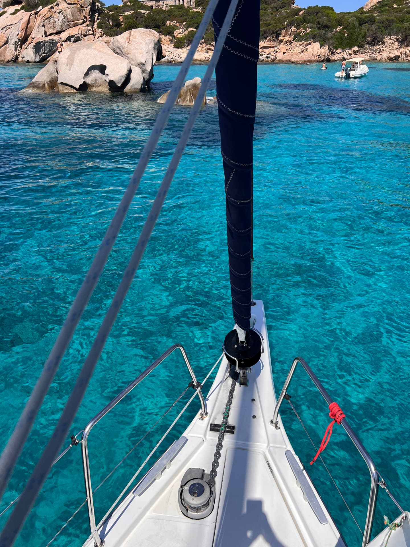 View over a sailing yacht bow into clear turquoise water