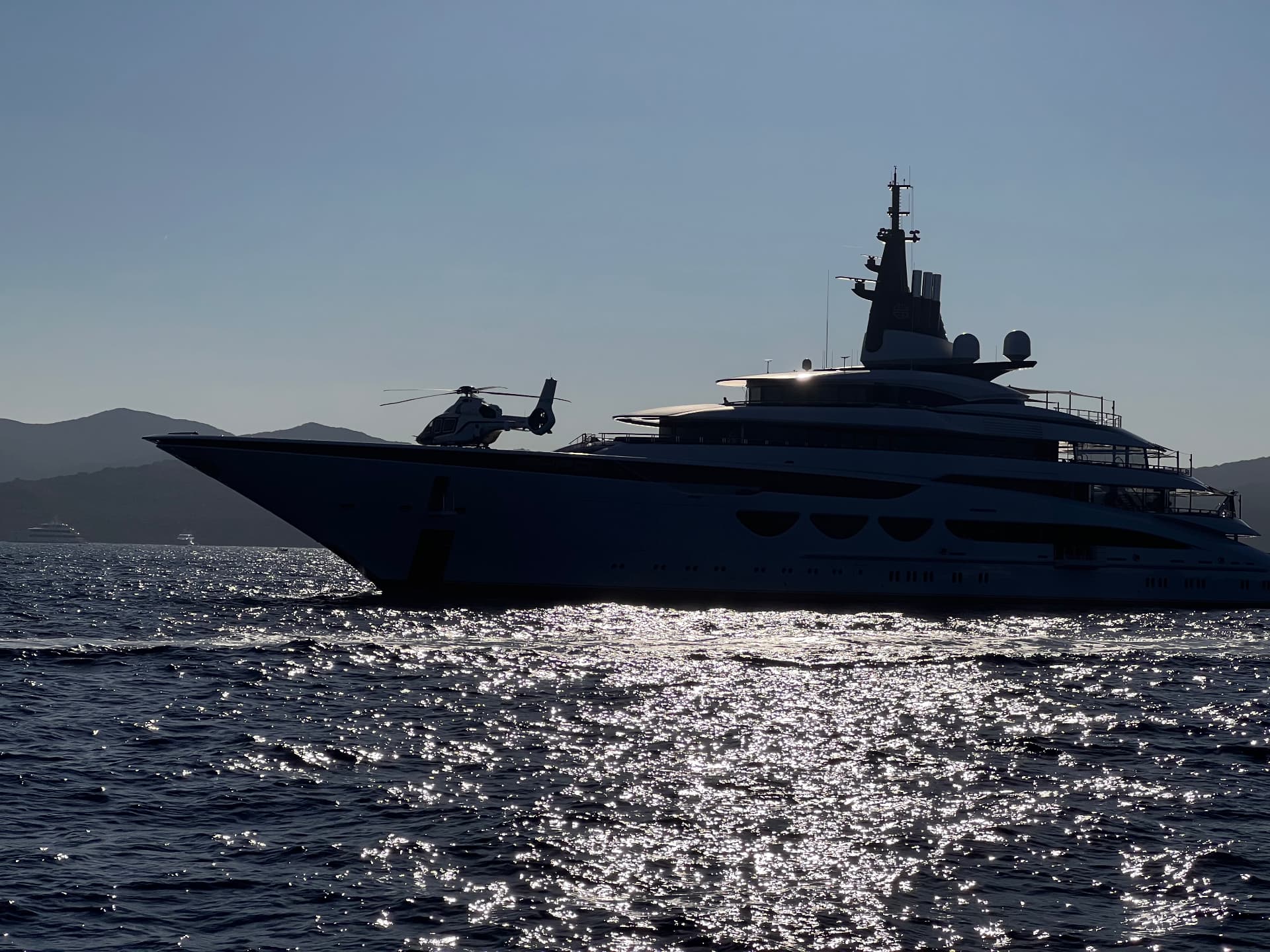 Superyacht and helicopter silhouetted against the Mediterranean light