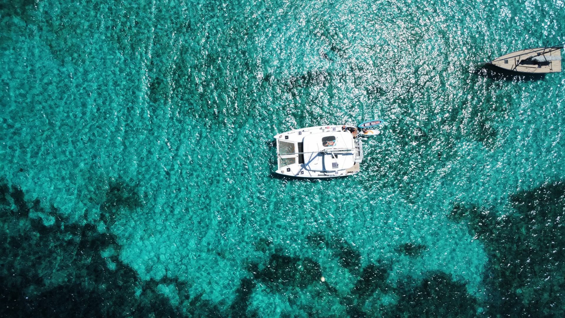 Catamaran anchored in clear water viewed from directly above