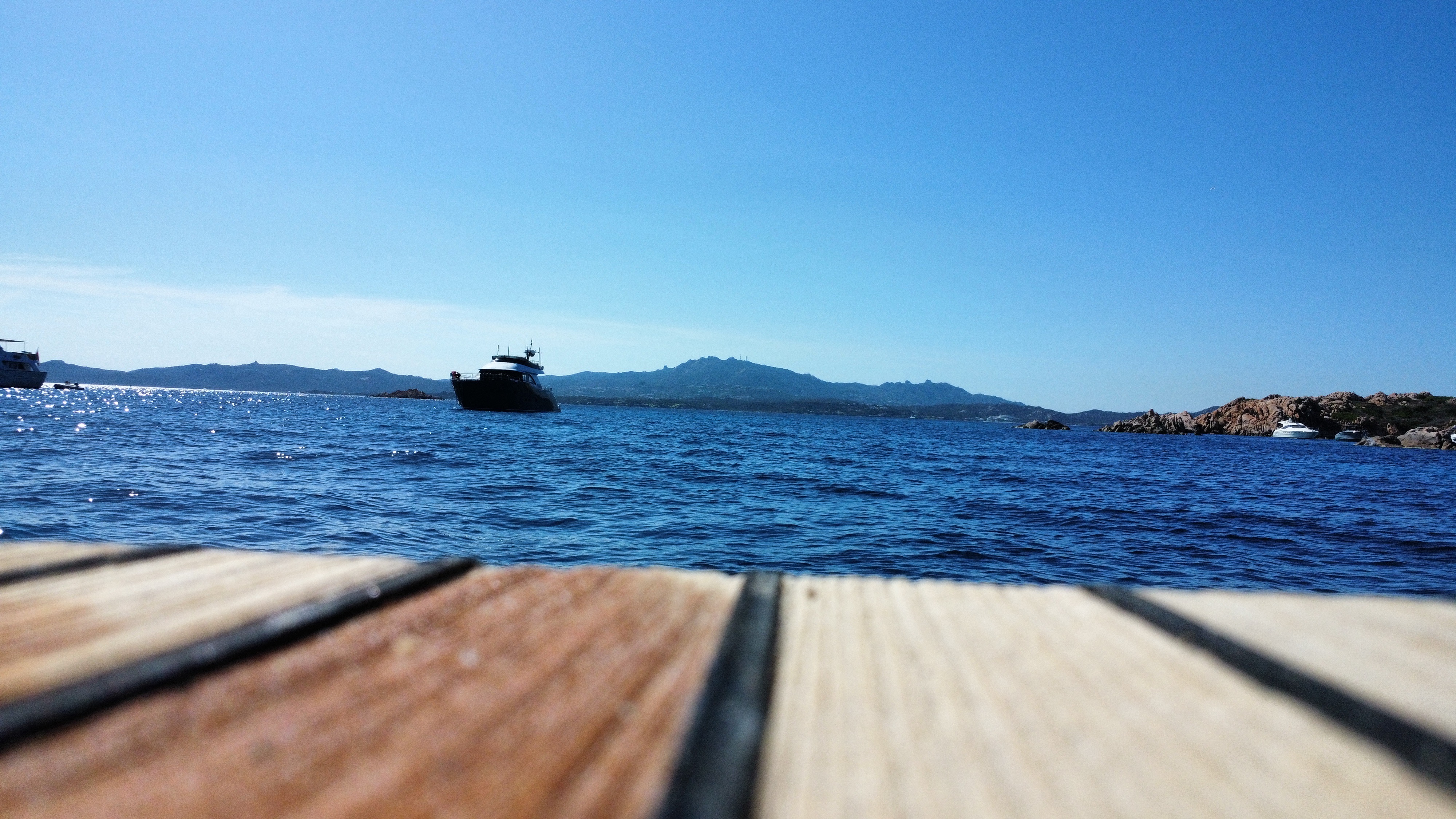 View from a teak yacht deck across deep blue Mediterranean water