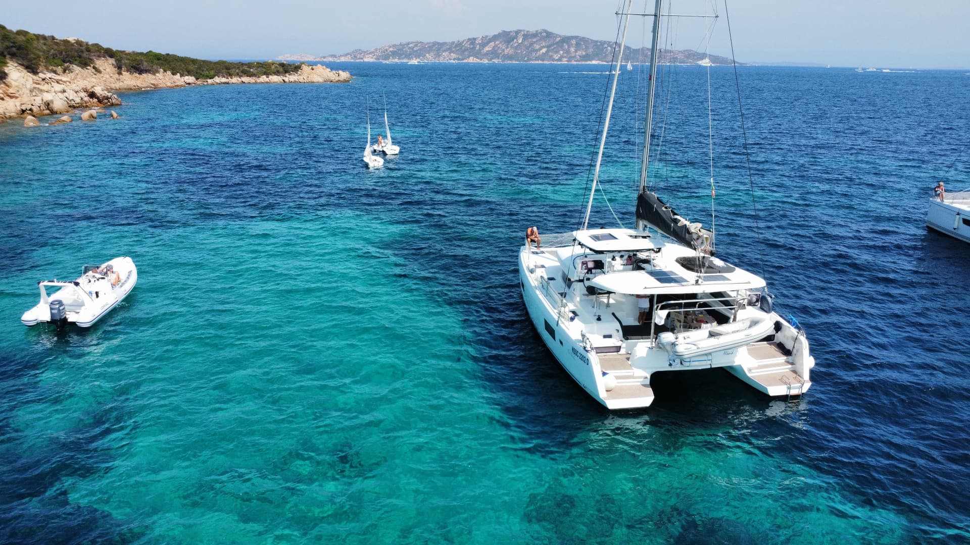 Sailing catamaran anchored over turquoise water in Sardinia